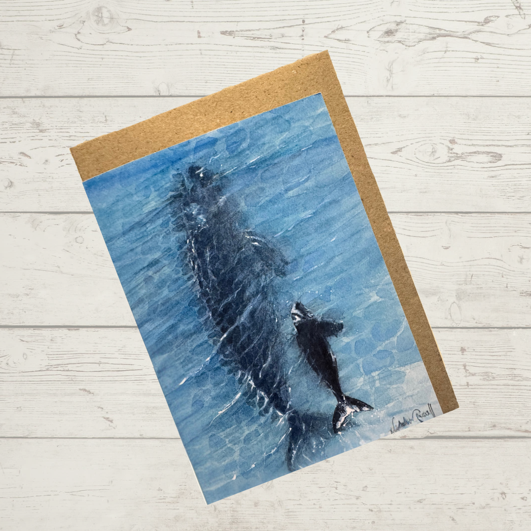 Image of actual card with natural coloured kraft paper envelope. Image depicts a mother whale and her calf swimming in the ocean as seen from a bird's eye view.