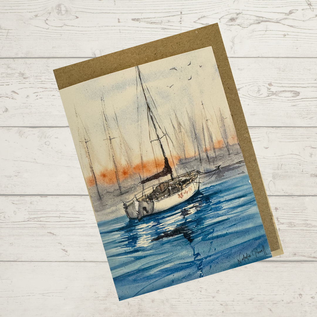 Image of actual card with natural coloured kraft envelope. Image depicts a sailboat moored in a marina.