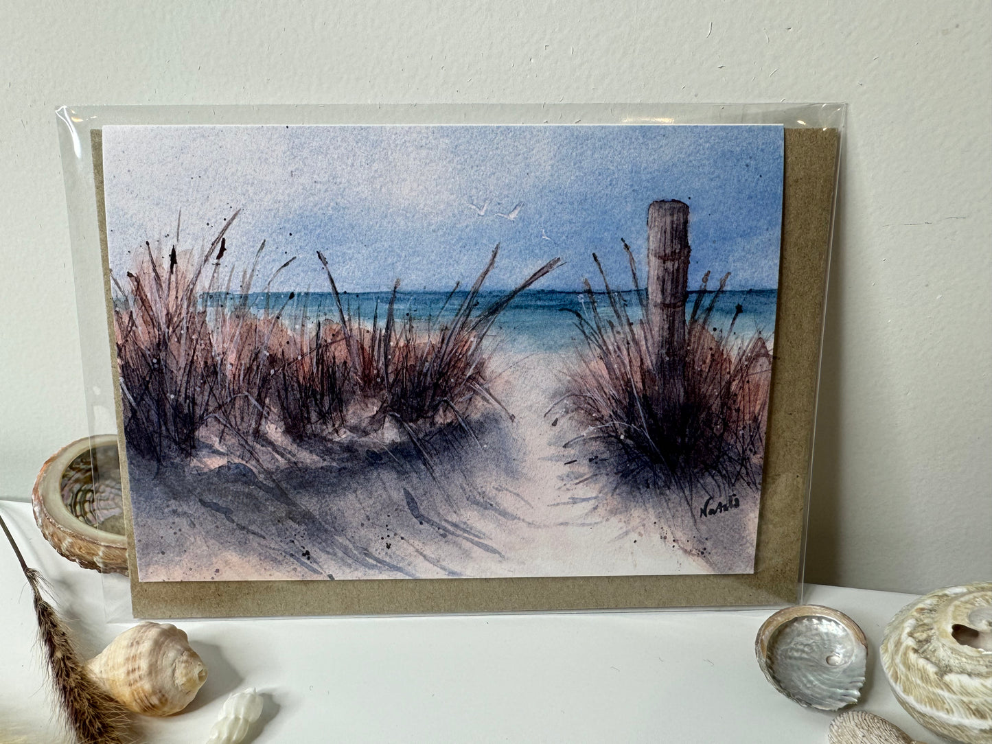 Image of actual card with natural coloured kraft paper envelope. Image depicts a sandy path through beach grass and old fence post to the beach.